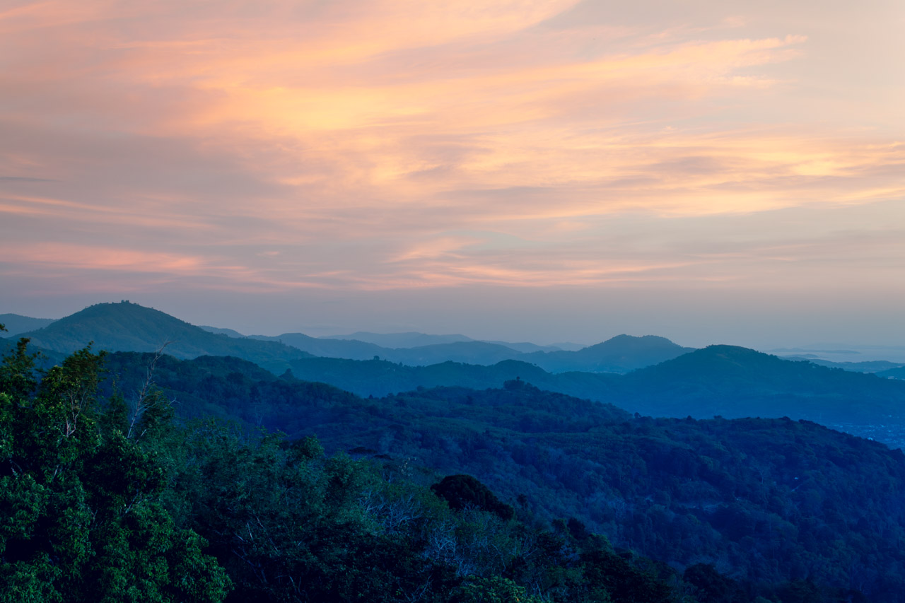 Layers of mountain ridges glowing in soft sunset light near Phuket, Thailand.
