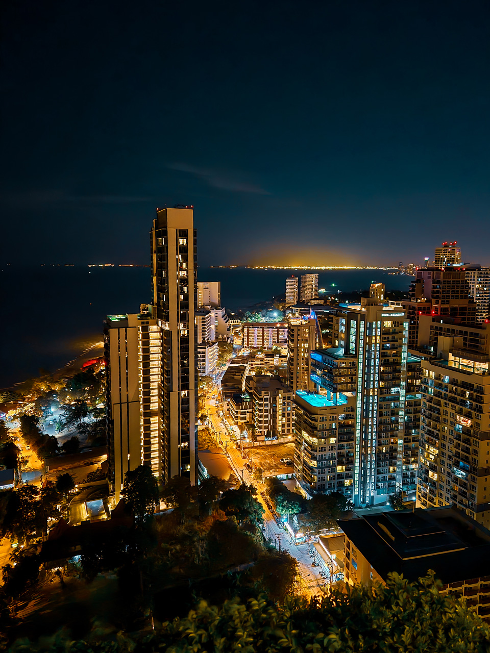 Night view of Pattaya skyline with city lights, high-rise buildings, and the sea in Thailand.
